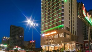 Un hotel di grandi dimensioni con numerose finestre illuminate e un cartello ben visibile che indica la presenza di un albergo.