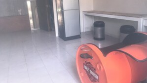 A kitchen with a refrigerator, a trash bin, and a Harley-Davidson motorcycle. - Palio Home - Hostel (Ko Pha-ngan)
