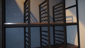 A metal shelving unit with multiple compartments against a plain wall. - Palio Home - Hostel (Ko Pha-ngan)