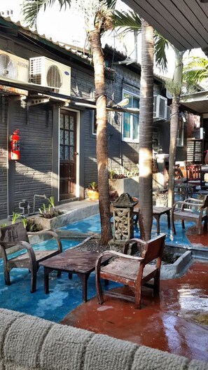 An outdoor pool area with wooden furniture and palm trees. - Palio Home - Hostel (Ko Pha-ngan)