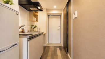 A narrow hallway with a kitchen area on one side, a door at the end, and a thermostat on the wall.