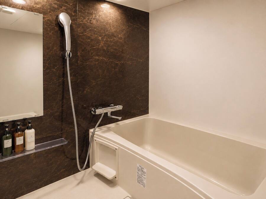 A modern bathroom with a bathtub, a showerhead, and a mirror.