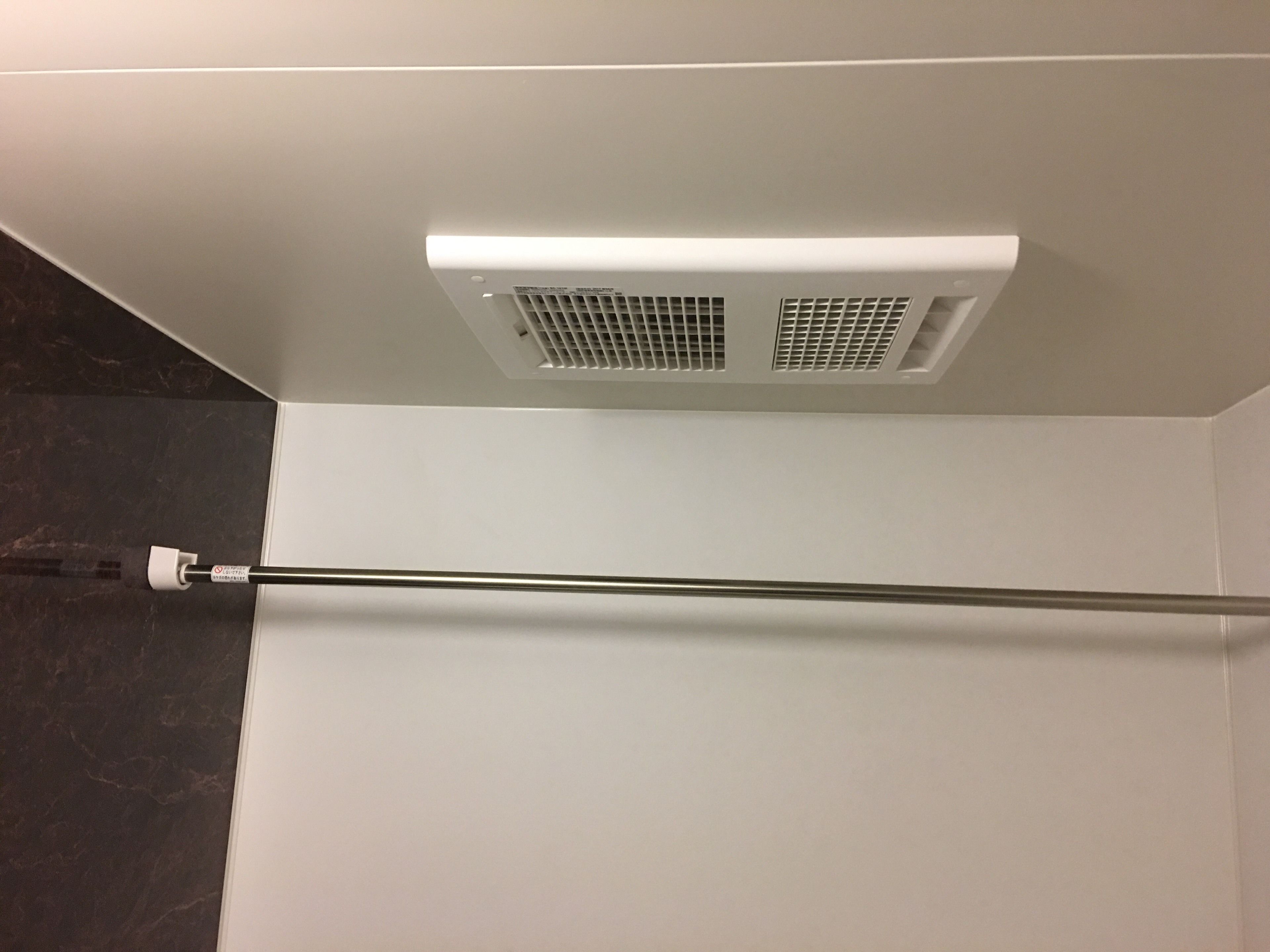 A bathroom with a white ceiling, a visible vent, and a towel rack.
