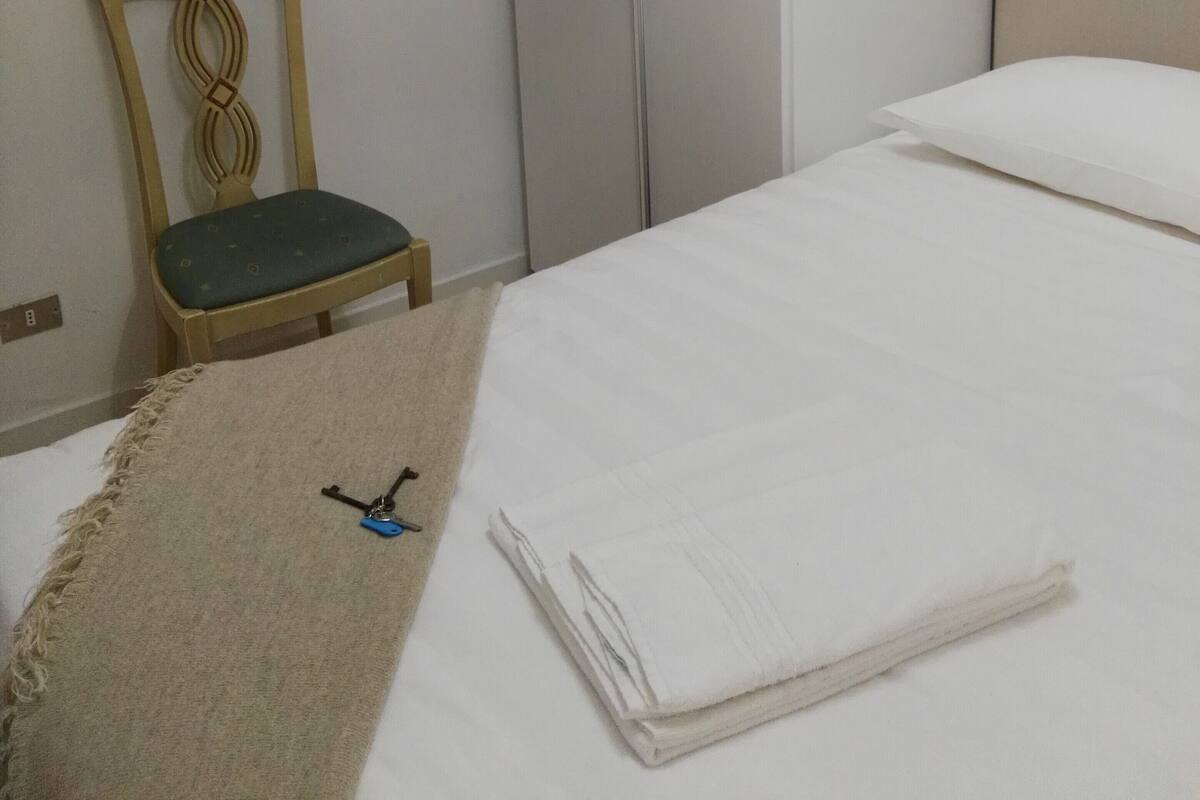 A hotel room with a bed, a chair, a framed picture on the wall, and a closet.