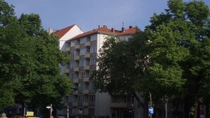 A multi-story building with a red-tiled roof, surrounded by trees.