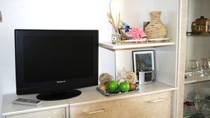 A flat-screen TV, a remote control, and a tray with decorative items on a cabinet.