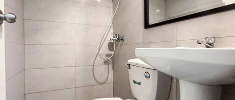 Un baño pequeño y moderno con inodoro, lavamanos y ducha.