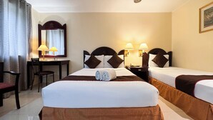 Camera d'albergo con due letti singoli, una scrivania con sedia, uno specchio e due abat-jour.
