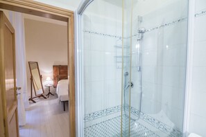 Une salle de bain avec une douche à parois de verre, une porte en bois et un miroir.