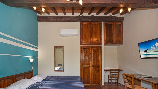 A bedroom with a bed, a desk, a chair, a TV, and wooden cabinets. - Villa Rinascimento Dependance (Lucca)