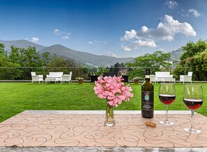A table with a bottle of wine, two glasses, and pink flowers.