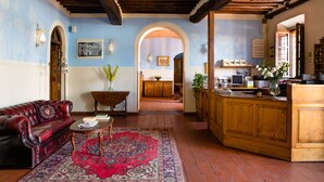 A traditional interior with a red leather sofa, a wooden dining table, and a kitchen area with wooden cabinets and a countertop. - Villa Rinascimento Dependance (Lucca)