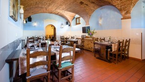 A dining area with multiple tables and chairs, brick ceiling, and blue walls. - Villa Rinascimento Dependance (Lucca)