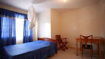 Un dormitorio con una cama, un escritorio y dos sillas.
