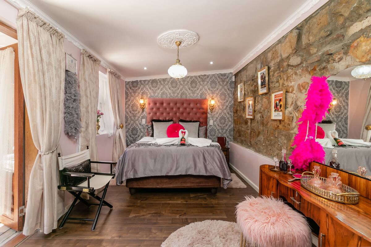 Een slaapkamer met een gestapeld hoofdeinde, een kaptafel met spiegel en een dressoir.