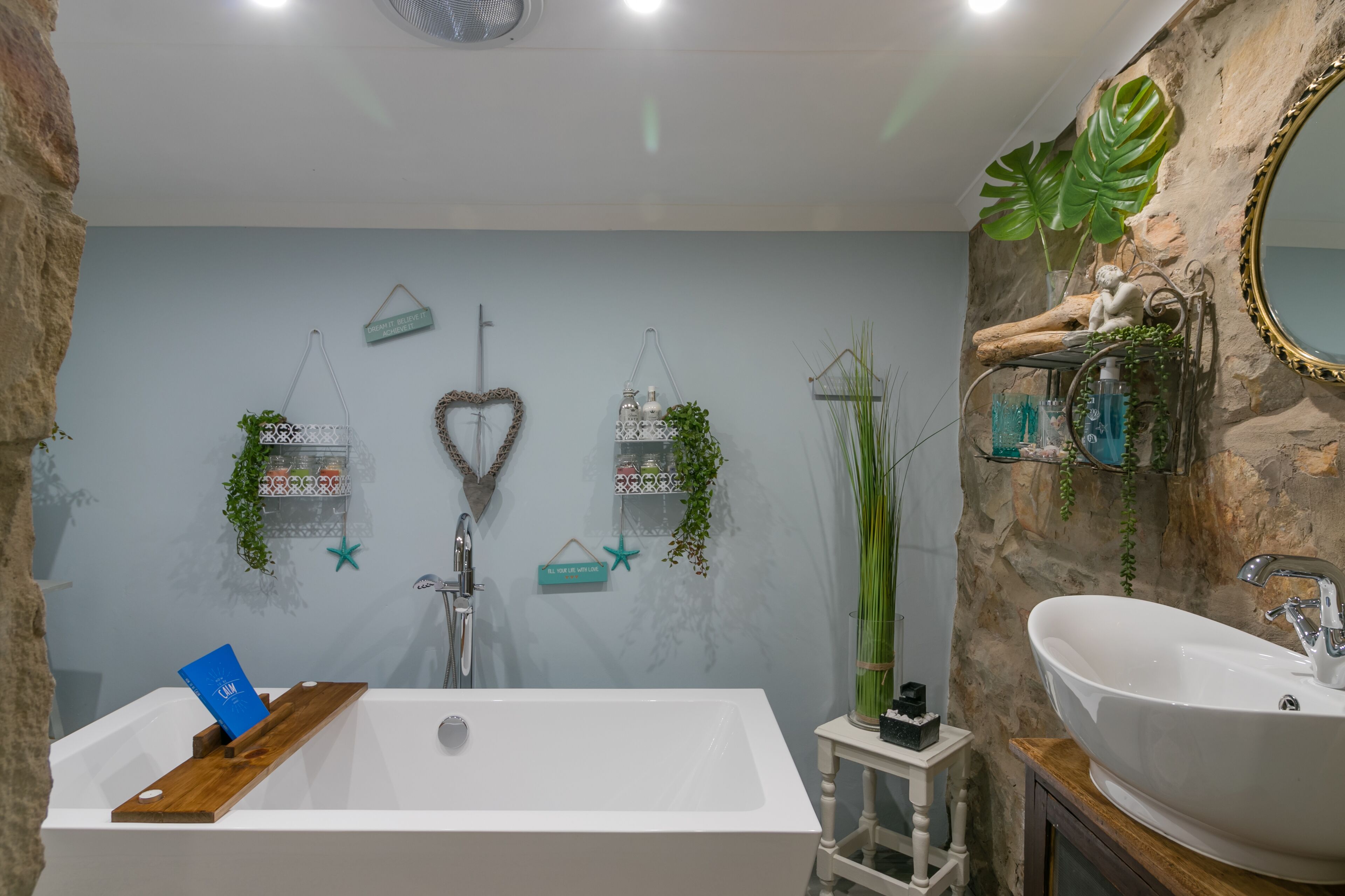 Ein Badezimmer mit einer weißen Badewanne, einem weißen Waschbecken und dekorativen Pflanzen.
