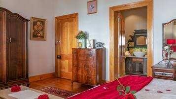 A bedroom with a bed, wooden dresser, and a bathroom visible through an open door.