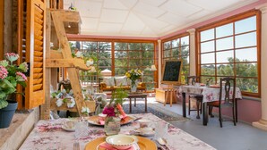 A dining area with a table set for four, surrounded by large windows and wooden furniture. - Bettys Boutique Hotel (Mossel Bay)