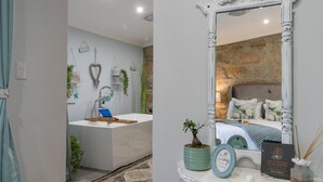 A bathroom with a bathtub, sink, and decorative plants. - Bettys Boutique Hotel (Mossel Bay)