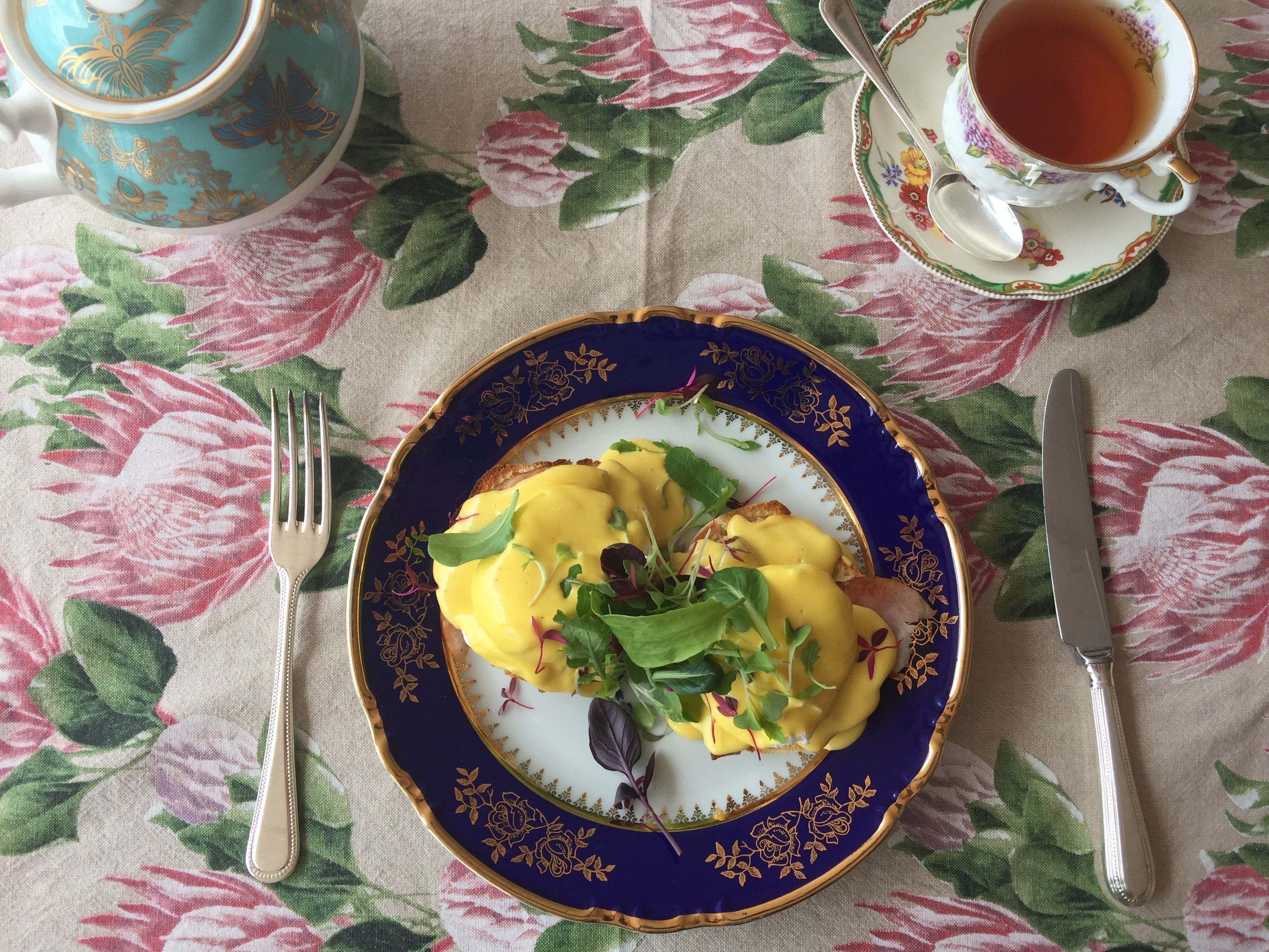 A plate of food with a fork and knife on a tablecloth with a floral pattern.
