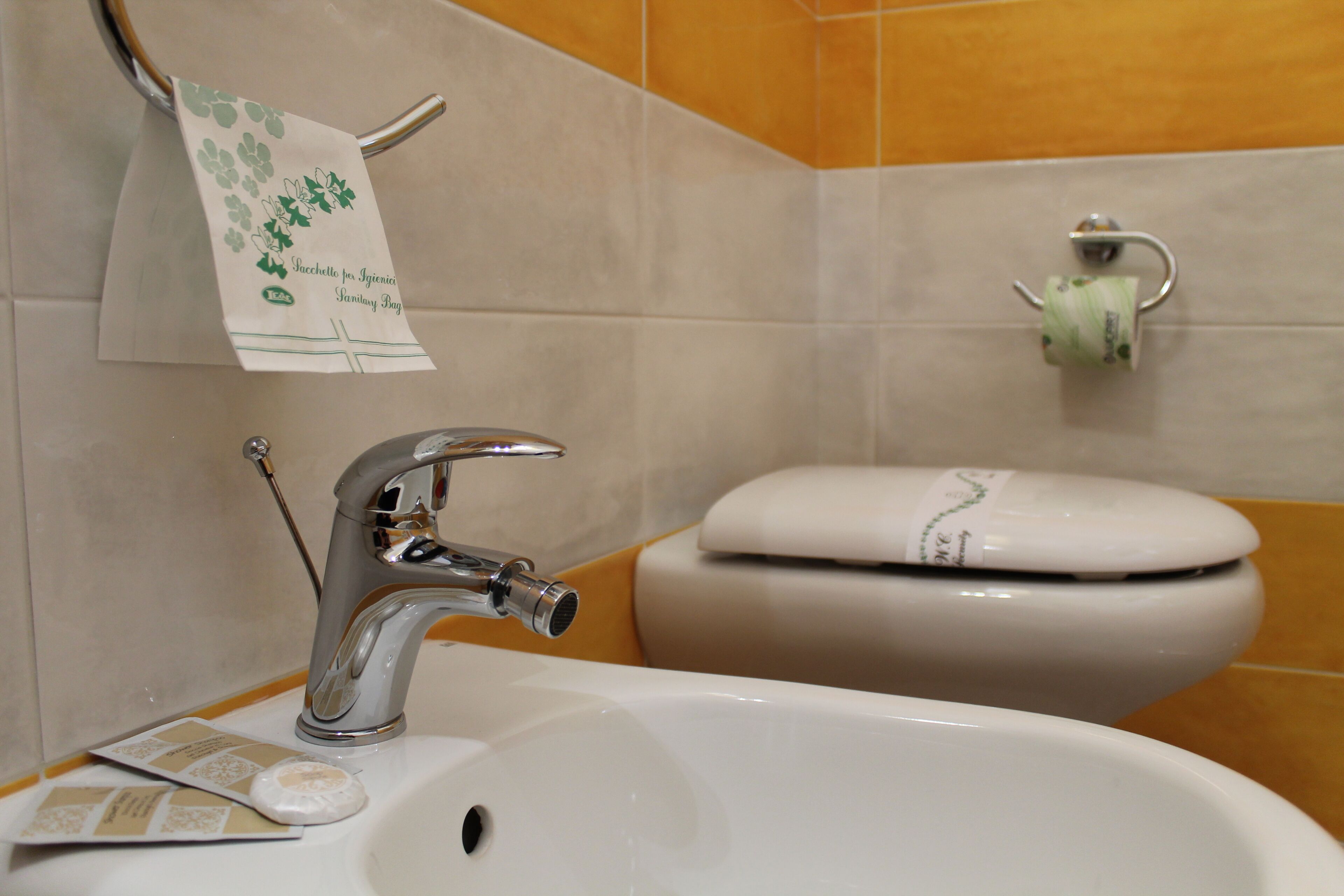 A bathroom with a white sink, a chrome faucet, a toilet, and a towel hanging on a rack.