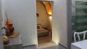 Ein Hotelzimmer mit Bett, Nachttisch, Blumen in einer Vase und einer Duschkabine.