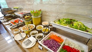 Een buffet met diverse gerechten, waaronder salades, groenten en sushi.