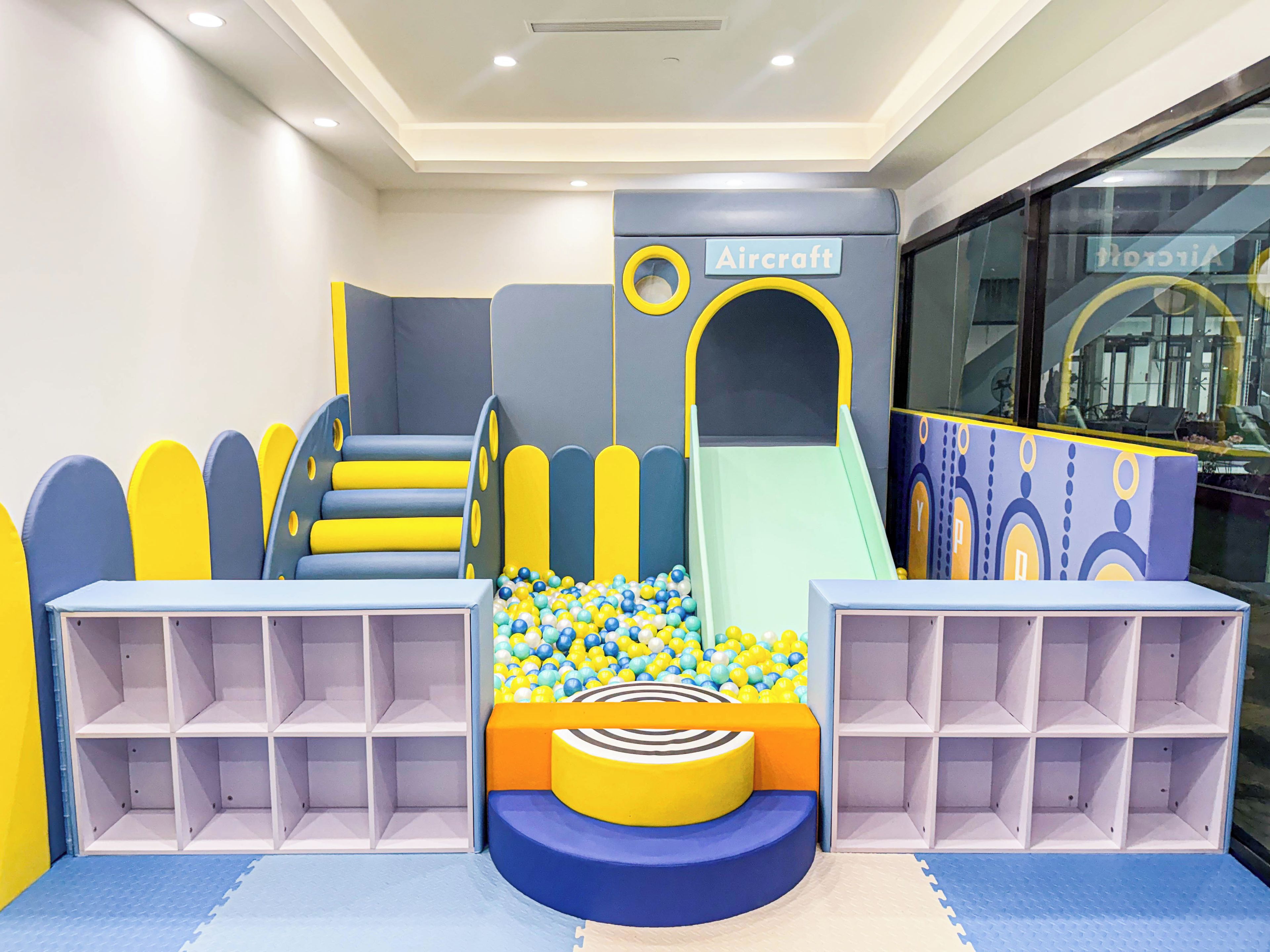 A children's play area with a slide, climbing steps, and ball pit.