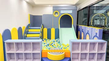 A children's play area with a slide, climbing steps, and ball pit.