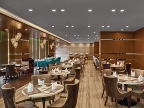 A spacious restaurant with multiple tables and chairs, wooden paneling, and modern lighting fixtures. - TUI SUNEO Olympia Phnom Penh (Phnom Penh)