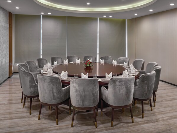 A conference room with a round table, grey upholstered chairs, and a vase with red flowers. - TUI SUNEO Olympia Phnom Penh (Phnom Penh)