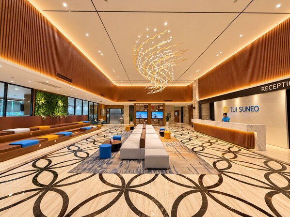 A spacious lobby with a reception desk, seating area, and a large screen displaying a video.