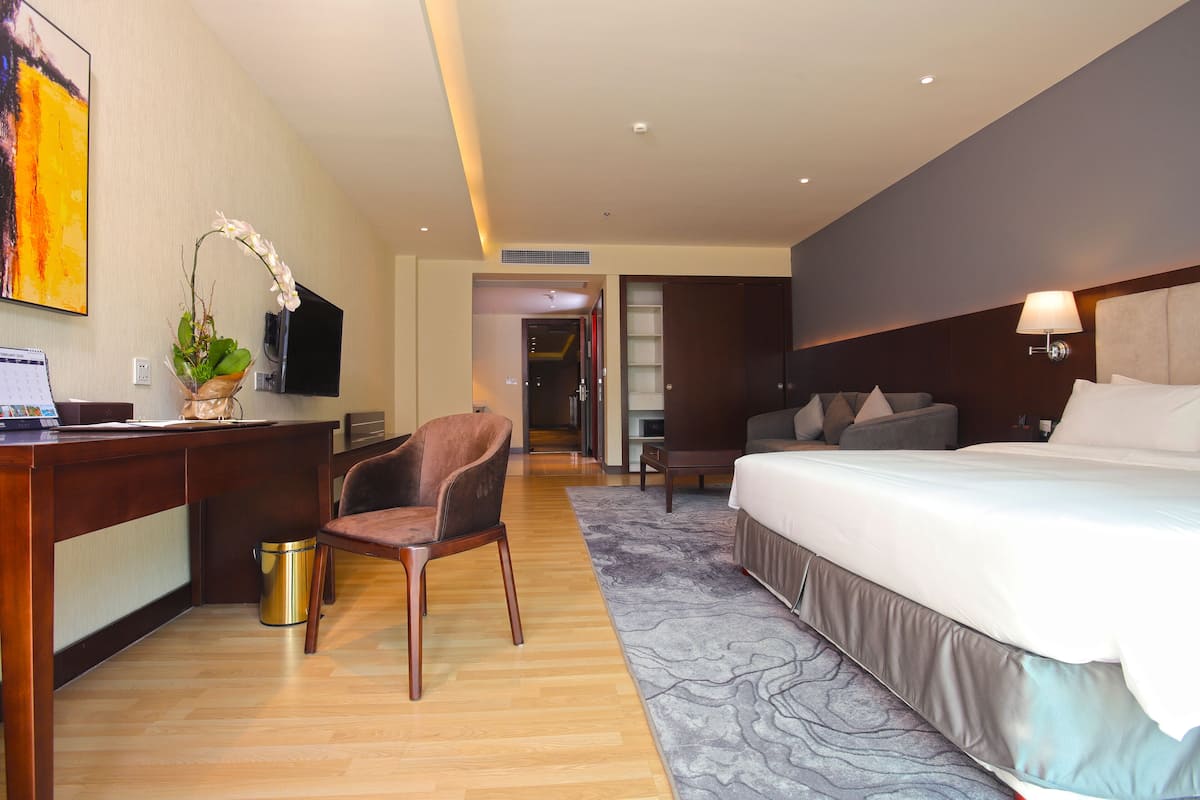 A hotel room with a bed, desk, chair, and a television.