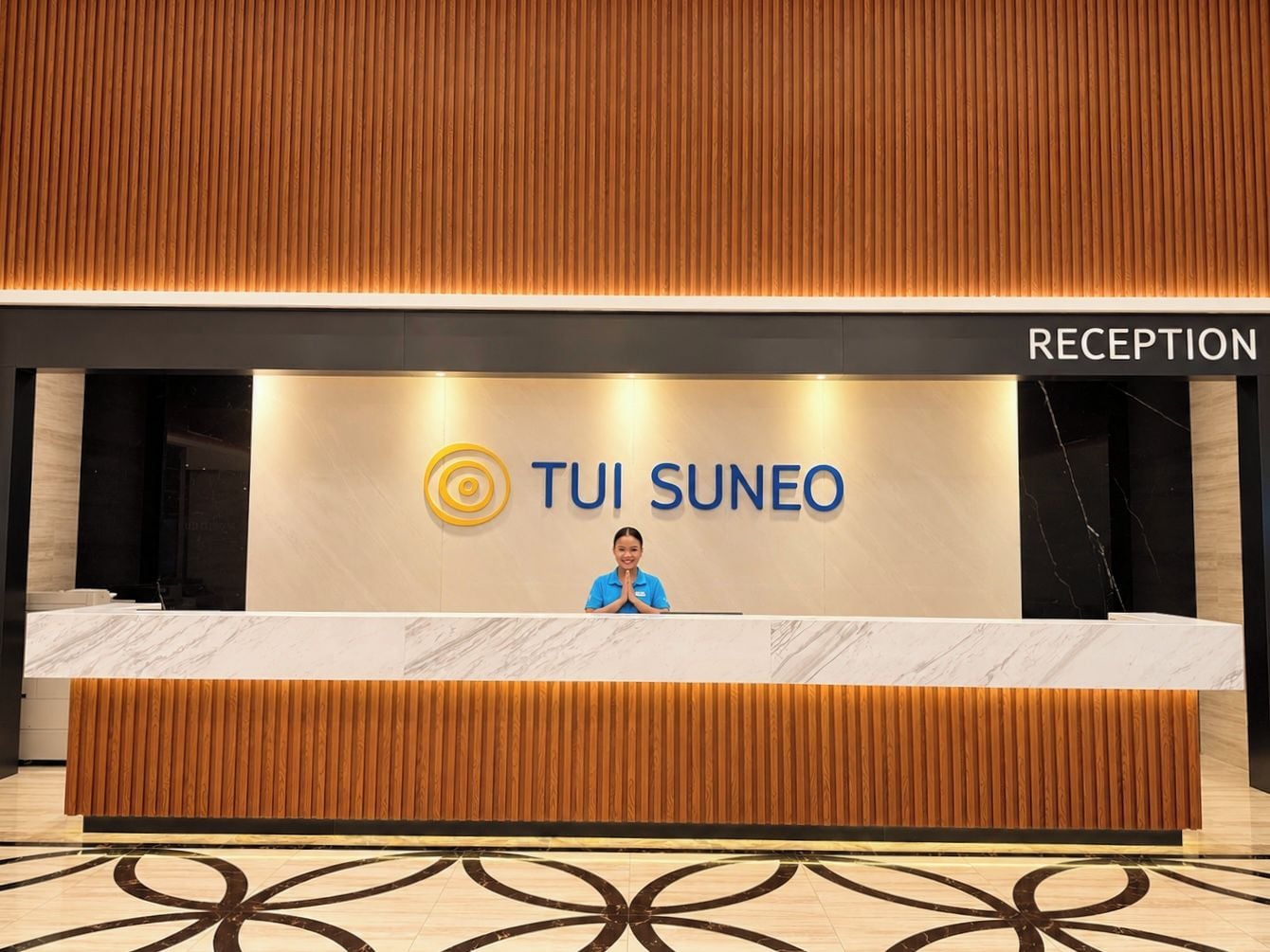 A reception desk with a 'RECEPTION' sign above it, a 'TUI SUNEO' logo, and a person standing behind the desk.