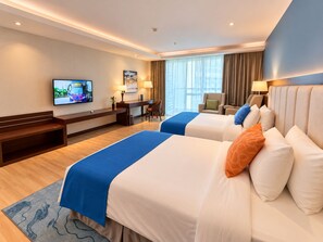 A hotel room with two beds, a desk, a chair, a TV, and a window with curtains. - TUI SUNEO Olympia Phnom Penh (Phnom Penh)