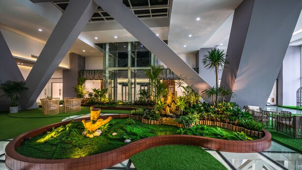 Een moderne atriumruimte met een centrale tuin, glazen balustrades en modern meubilair.