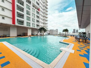 A swimming pool with a tiled deck, surrounded by a multi-story building with balconies. - TUI SUNEO Olympia Phnom Penh (Phnom Penh)
