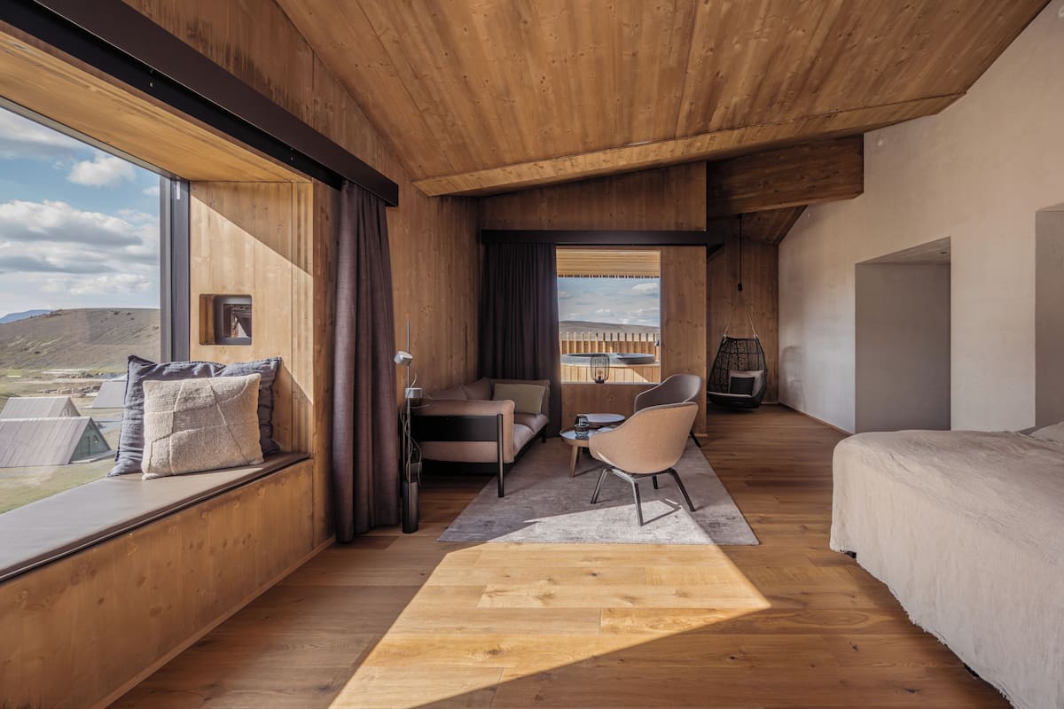 A bedroom with a large window, wooden ceiling, and a bed.