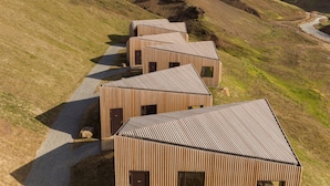 A row of wooden cabins with sloped roofs, arranged along a gravel path in a hilly landscape. - Highland Base Kerlingarfjöll (Hrunamannahreppur)