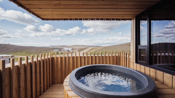 A wooden deck with a hot tub and a view of a rural landscape. - Highland Base Kerlingarfjöll (Hrunamannahreppur)