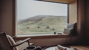 A cozy room with a large window overlooking a grassy landscape with small houses. - Highland Base Kerlingarfjöll (Hrunamannahreppur)