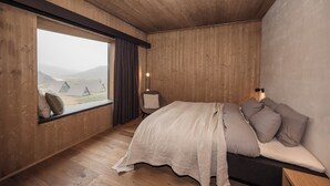 A bedroom with a large window, wooden walls, a bed with pillows, and a chair. - Highland Base Kerlingarfjöll (Hrunamannahreppur)