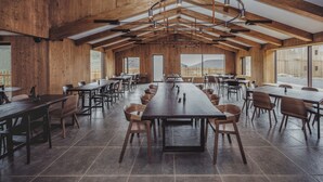 A spacious dining area with long wooden tables and chairs, high ceilings with exposed beams, and large windows offering views of the outdoors. - Highland Base Kerlingarfjöll (Hrunamannahreppur)