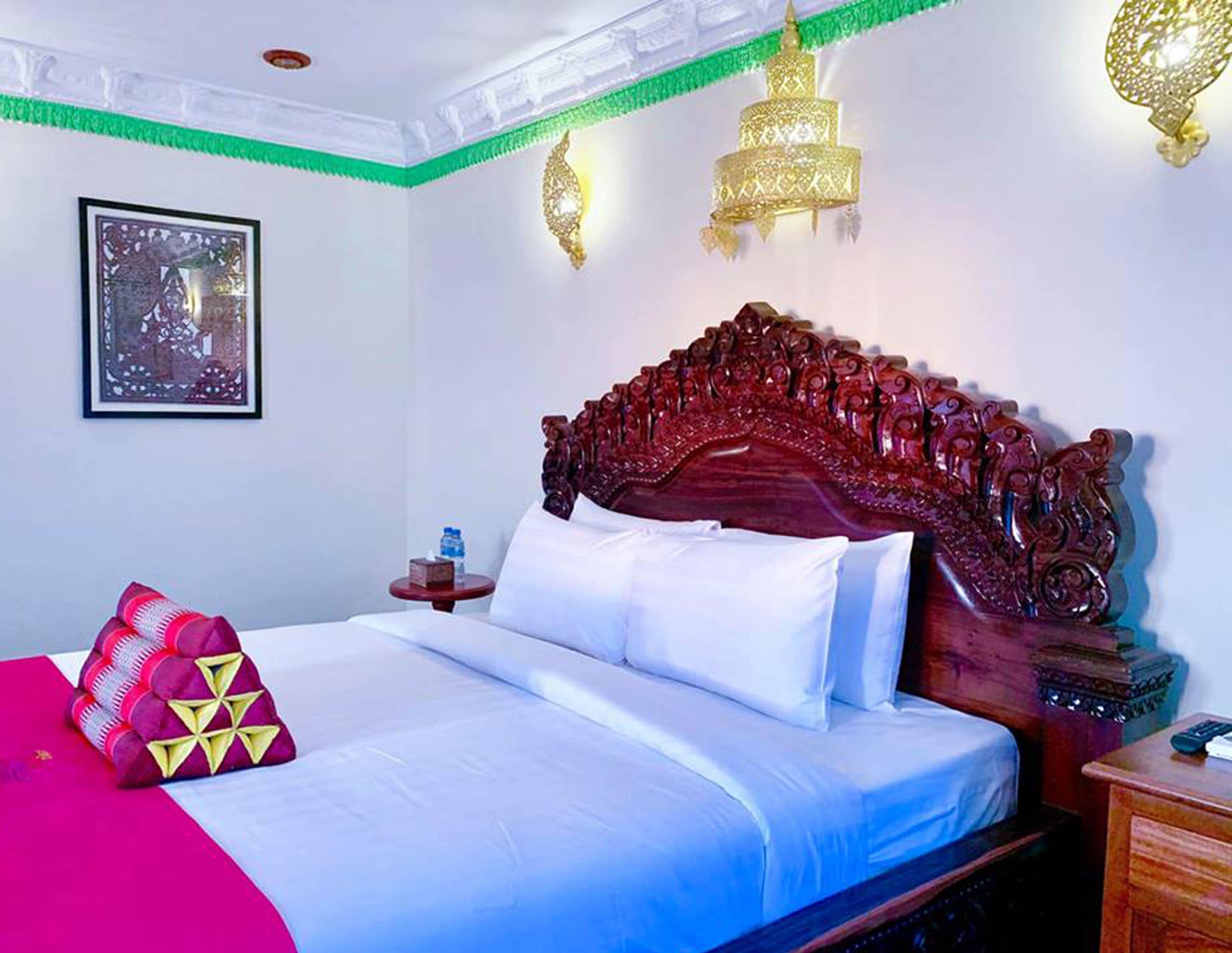 Une chambre d’hôtel avec un grand lit, une œuvre d’art encadrée au mur et des appliques murales décoratives.