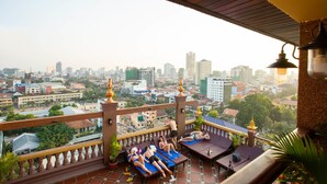Un balcón con vistas a la ciudad, sillones de descanso y una mesita con lámpara.
