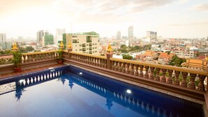 Una piscina en la azotea con vistas a un paisaje urbano, que incluye edificios y un templo.