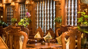 Un interior de madera tradicional con muebles ornamentados y plantas en macetas.