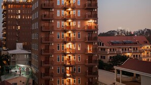 Un hotel de varios pisos con balcones, unidades de aire acondicionado y una terraza en la azotea.