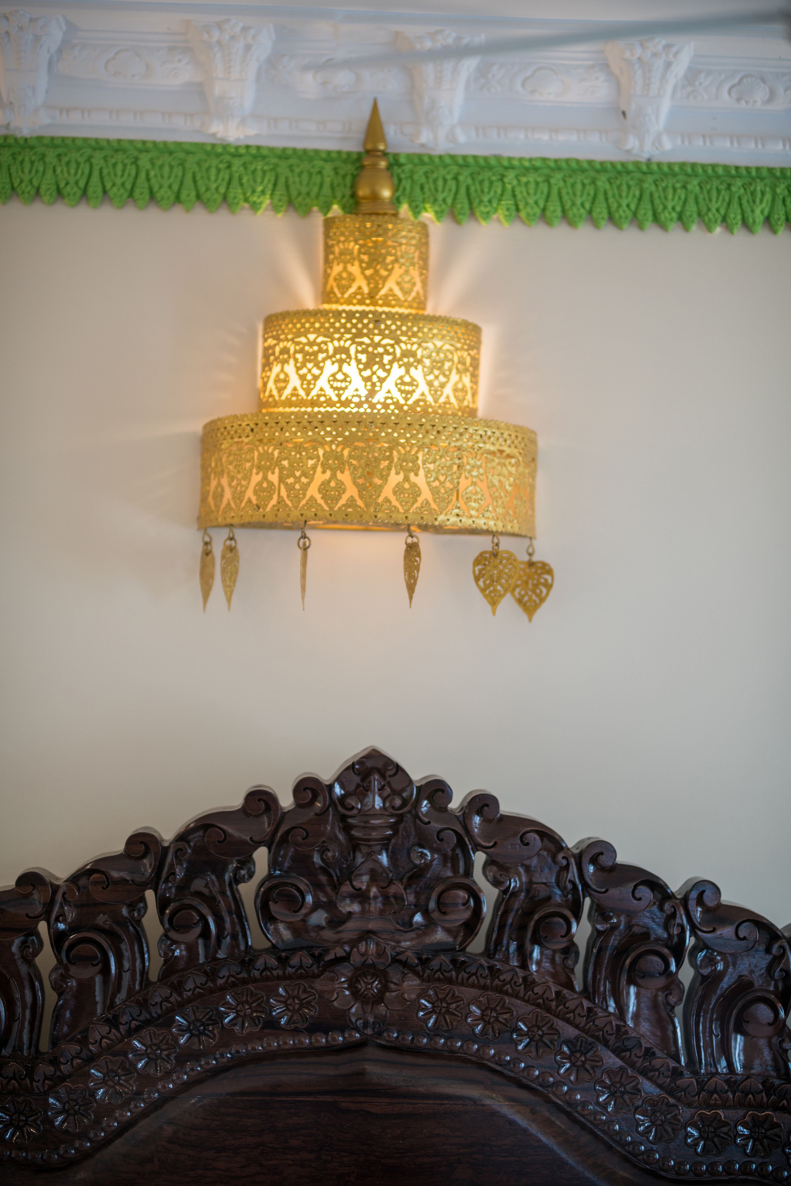 A bed with an ornate headboard and a decorative wall-mounted lamp with intricate patterns.