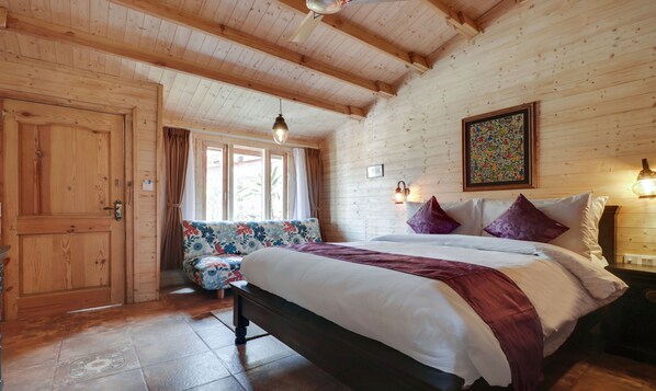 A wooden room with a bed, a bench, and a window. - Treebo Premium Blue Mountain Country Club And Resort (Siliguri)
